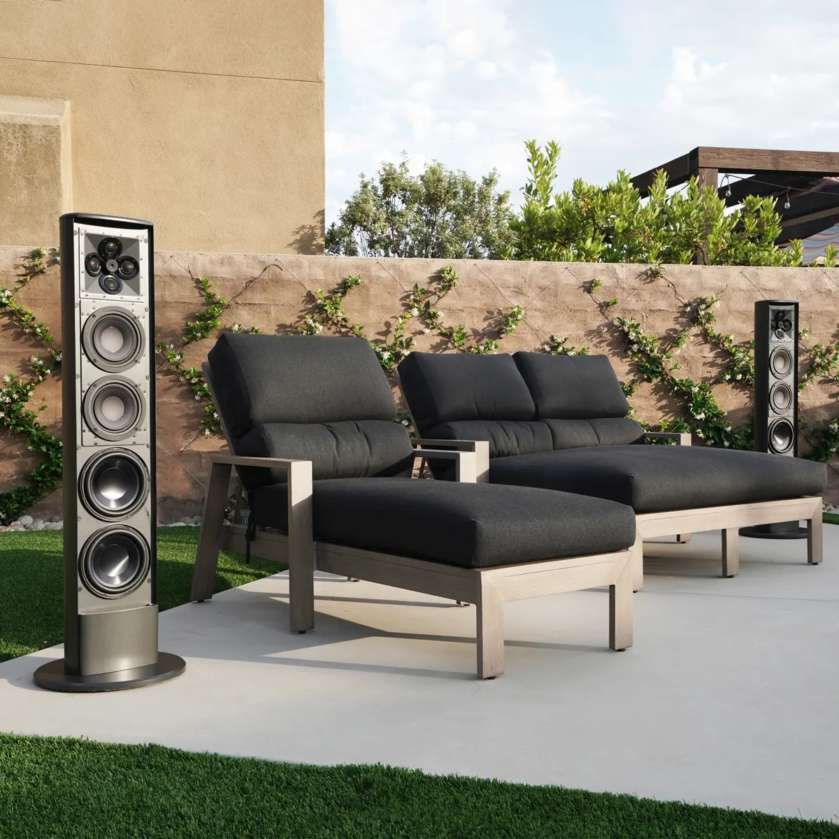 James Loudspeaker Outdoor Tower neben Loungemöbeln auf einer Terrasse