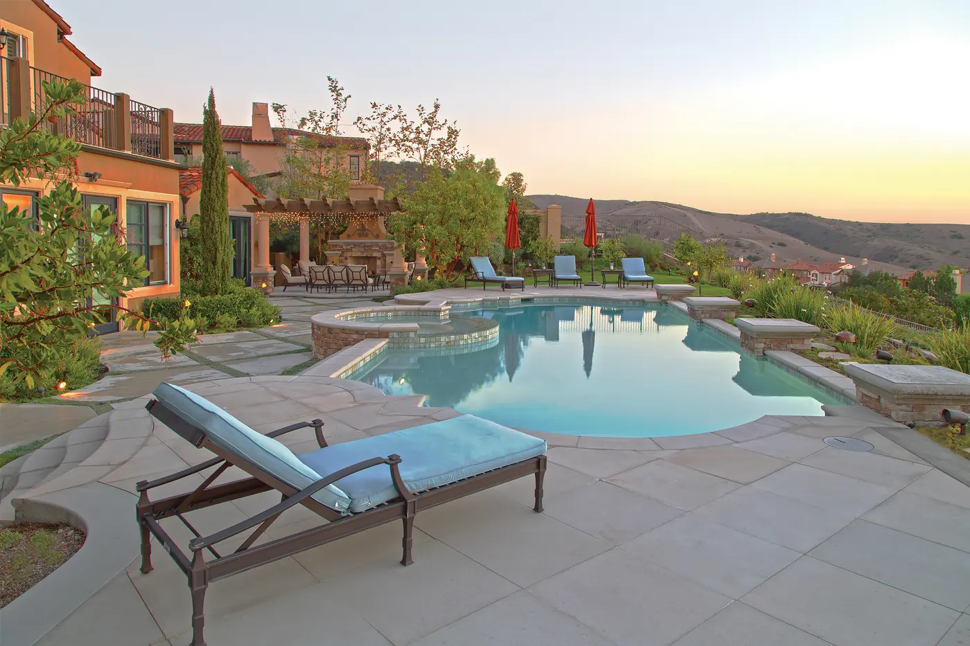 Terrasse mit Pool am Abend, ein Sonance Landscape-Satellit steht im Beet am Rand